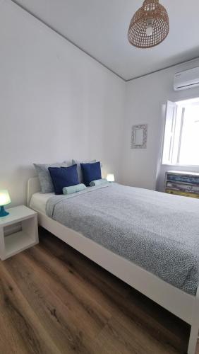 1 dormitorio blanco con 1 cama grande con almohadas azules en Happen!ng en Faro