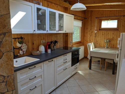 a kitchen with white cabinets and a sink and a table at Gabi háza in Balatonalmádi