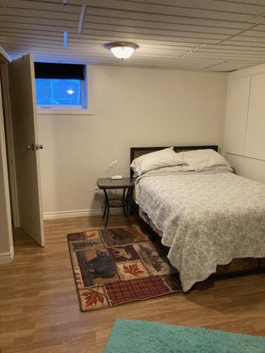 a bedroom with a bed and a table on a rug at Executive Guest Suite in Edmundston