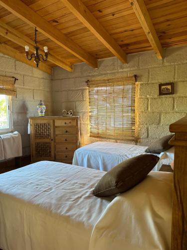 um quarto com 2 camas com lençóis brancos e uma janela em Cabañas Jassí em Querétaro