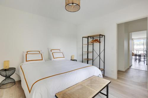 een witte slaapkamer met een groot bed en een tafel bij La Résidence Alpha Viroflay 201 - 1 chambre - 4 pers in Viroflay