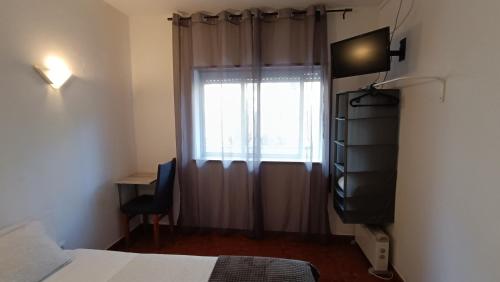 a bedroom with a bed and a window with a television at Residencial S. Gião in Valença