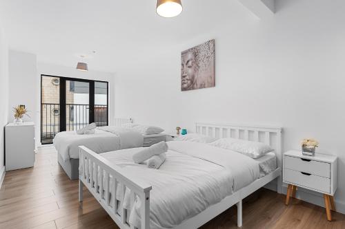 2 letti in una camera da letto con pareti bianche e pavimenti in legno di Three Bedroom In Heart Of Central London MR4 a Londra