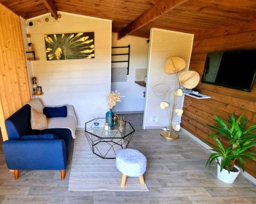 - un salon avec un canapé bleu et une table dans l'établissement Nuit d'Amour - Chalet cocooningchauffé/climatisé, à Carsac-Aillac