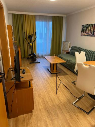 uma sala de estar com uma televisão, um sofá e uma mesa em Cara Apartments em Warmbad Villach