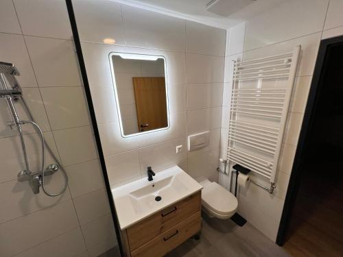 uma casa de banho com um lavatório, um WC e um espelho. em Cara Apartments em Warmbad Villach