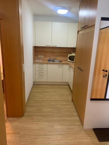 uma pequena cozinha com armários brancos e piso em madeira em Cara Apartments em Warmbad Villach