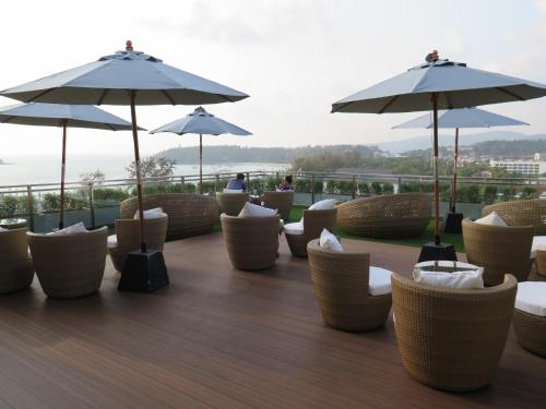 a row of chairs and umbrellas on a deck at Sugar Palm Grand Hillside - SHA Plus in Kata Beach