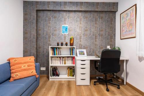 a living room with a blue couch and a desk and a book shelf at Casa Coli in Sabiñánigo