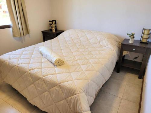 białe łóżko w sypialni z dwoma stołami w obiekcie Hospedaje El Toltén w mieście Junín de los Andes