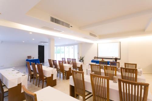 a dining room with white tables and wooden chairs at Sugar Palm Grand Hillside - SHA Plus in Kata Beach