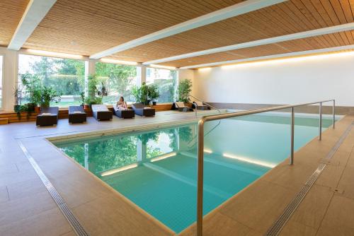 a swimming pool in a building with a woman sitting on a couch at Studio im Hotel Des Alpes in Flims