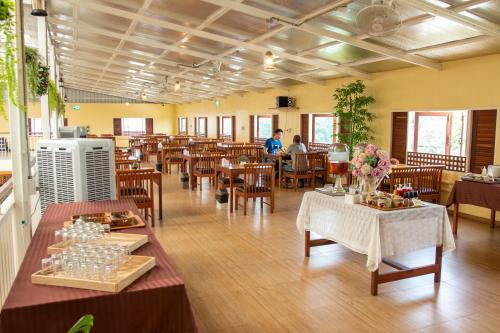 um restaurante com mesas e cadeiras e pessoas ao fundo em Nonnee Lampang Hotel em Lampang