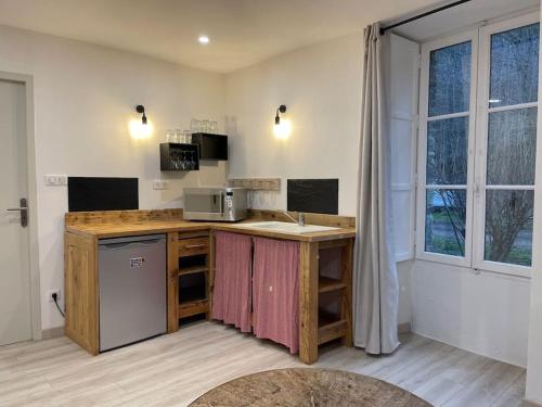 eine Küche mit einer Theke mit einer Spüle und einer Mikrowelle in der Unterkunft Le Moulin de Gueuzon in Rochefort-en-Terre