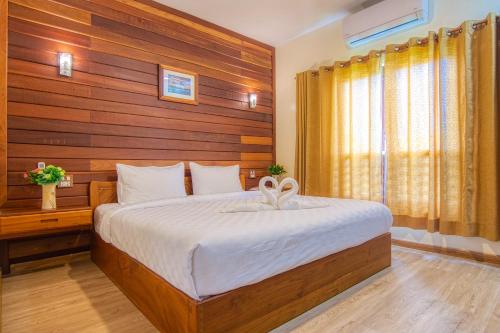a bedroom with a bed with a wooden wall at Nonnee Lampang Hotel in Lampang
