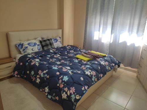 a bed with a blue comforter with flowers on it at CITY CENTER 2 in Shkodër