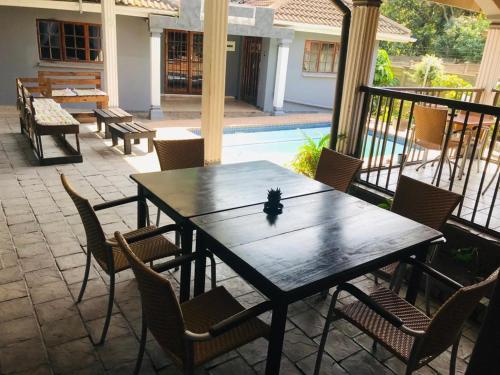 a wooden table and chairs on a patio with a pool at Nomusa's Bed and Breakfast in Richards Bay