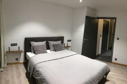 a bedroom with a large white bed and a mirror at Duplex style industriel à deux pas de la Place in Bertrix