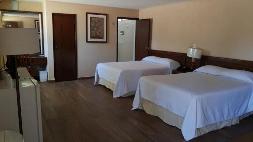 a hotel room with two beds with white sheets at Hotel Las Palmas Midway Inn in Matehuala