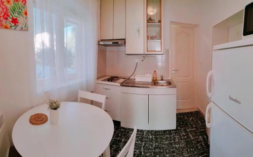 a small kitchen with a table and a white refrigerator at Apartmani Bojana in Rovinj