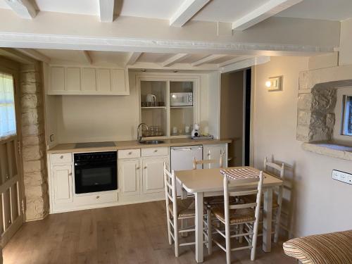 a kitchen with white cabinets and a table and chairs at Apartamentos Calm & Nature en Liebana in Cabezón de Liébana