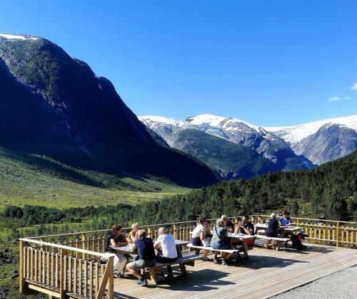 a group of people sitting at picnic tables on a deck overlooking mountains at Tungestølen in Veitastrond