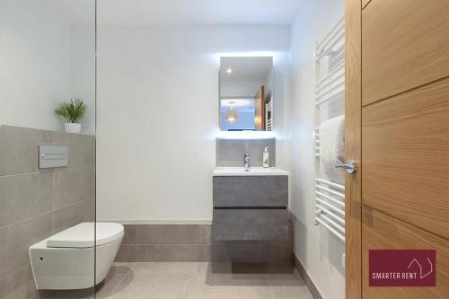 ein Badezimmer mit einem WC, einem Waschbecken und einem Spiegel in der Unterkunft Modern 3 Bedroom Apartment - Wokingham in Wokingham