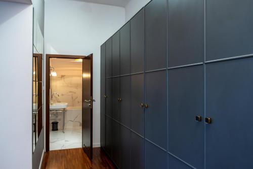 a hallway with blue cabinets and a bathroom with a sink at Mokotowska 7 in Warsaw