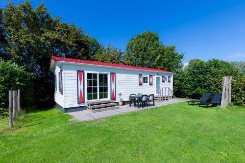 a small white cabin with a picnic table and chairs at Chalet Plantlust in Veere