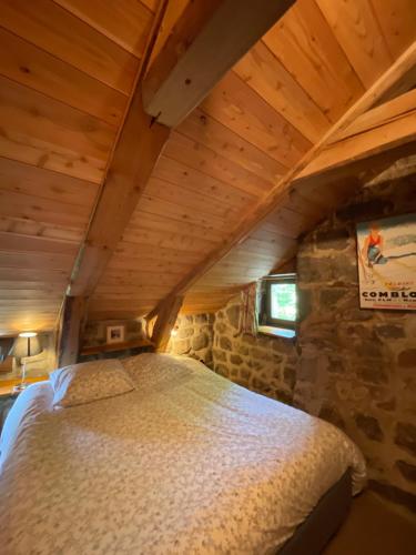 Una cama grande en una habitación con techo de madera. en Magnifique gite 14 personnes en bord de lac, en Devesset