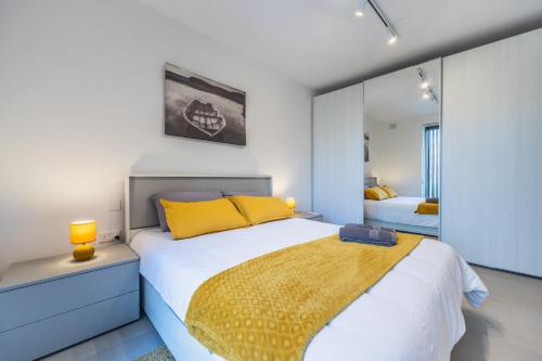 een slaapkamer met een bed met gele kussens en een spiegel bij Msida Park Residence C5 in Msida