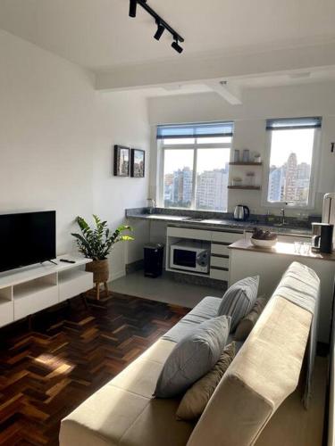ein Wohnzimmer mit einem Sofa und einer Küche in der Unterkunft Apartamento com vista espetacular na Cidade Baixa in Porto Alegre