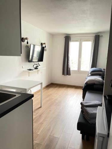 a room with a kitchen with a table and a tv at T2D Apartment - Suite BLG proche Disneyland Paris in Bussy-Saint-Georges