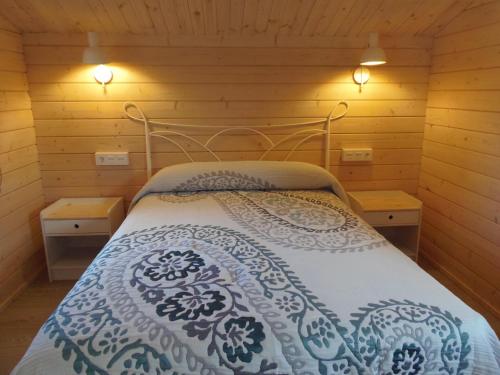 uma cama num quarto de madeira com duas luzes em El Naval de la Parra I em Sejas de Sanabria