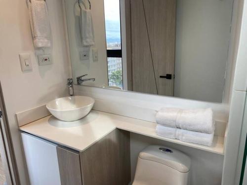 een badkamer met een wastafel, een toilet en een spiegel bij Apartamento academia 1201 in Bogota