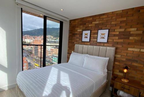 een bed in een slaapkamer met een bakstenen muur bij Apartamento academia 1201 in Bogota