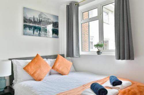 um quarto com uma cama com almofadas laranja e azul em Lovely flat near University of Reading em Reading