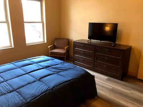 a bedroom with a bed and a tv and a chair at Cannery Square Apartment 104 in Sun Prairie