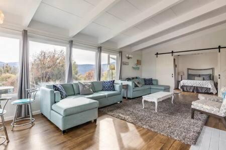 a living room with blue couches and a large window at Black Bear Haven Hot tub Pool table BBQ Darts in Oakhurst