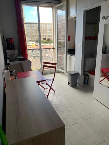 een kamer met een tafel en stoelen en een balkon bij STUDIO LE HAVRE PLAGE in Le Havre