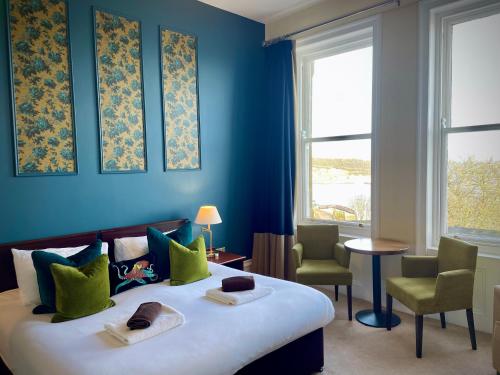 a bedroom with a bed with blue walls and windows at Weston Hotel in Scarborough
