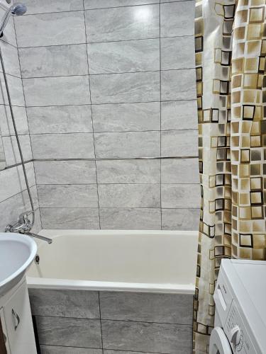 ein Badezimmer mit einer weißen Badewanne und einem Waschbecken in der Unterkunft Decebal 2 in Chişinău