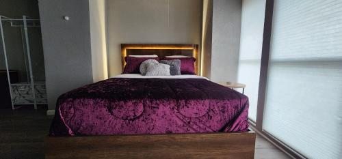 a bedroom with a large bed with a purple comforter at Large Condo in the heart of Las Colinas, near Dallas in Irving
