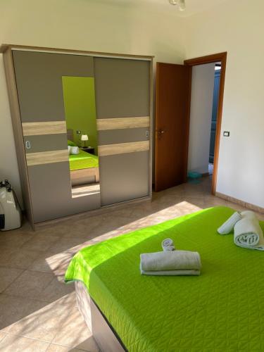 1 dormitorio con cama verde y espejo en VIKY apartments, en Buonfornello