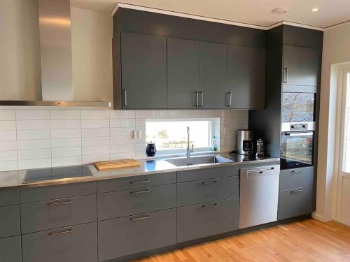 a kitchen with gray cabinets and a sink at Hus precis intill sjö in Lindome