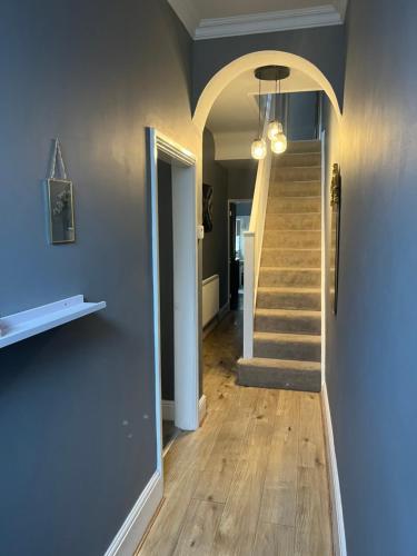 einen Flur mit einer Treppe mit blauer Wand in der Unterkunft Spacious 5 Bed Home in Birmingham Perfect for Families and Contractors! in Birmingham