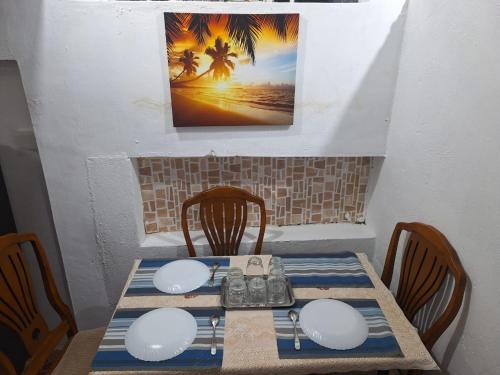 Triolet的住宿－SB Villa，一张桌子、四把椅子和一张墙上的照片