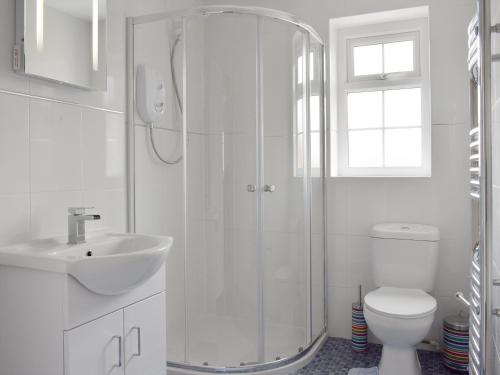 a white bathroom with a shower and a toilet at Rudda Farm House - Uk2491 in Staintondale