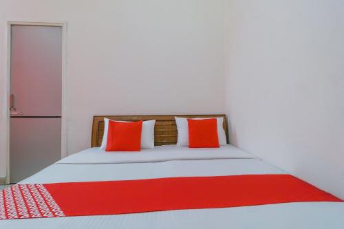 a bedroom with a bed with red and white pillows at OYO Flagship Mg Mehak Garden in Darbi
