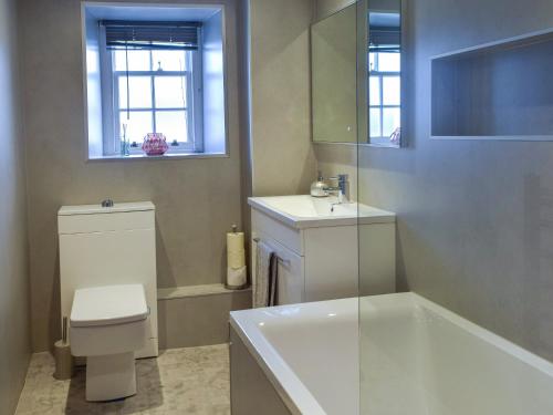 a bathroom with a tub and a toilet and a sink at Lochside Apartment in Inveraray